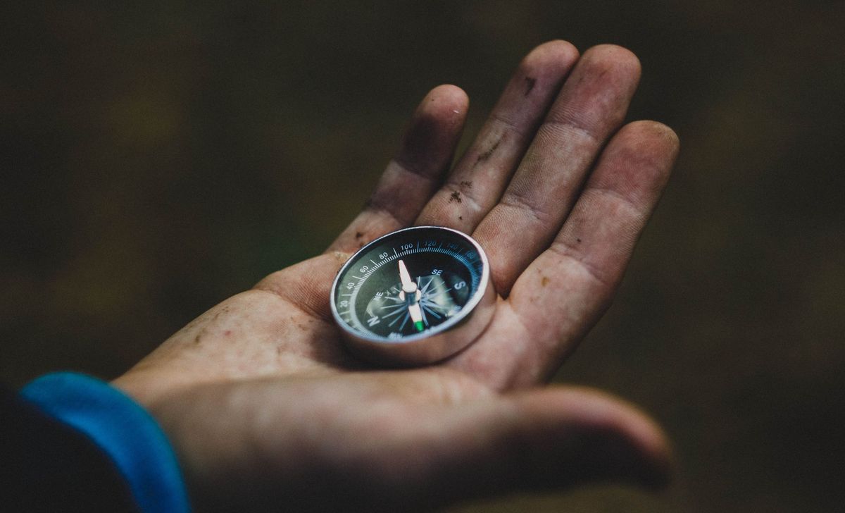 a man's hand holding a compass.